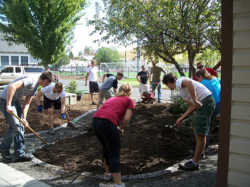 Students shoveling brown earth in a landscaping arrangement