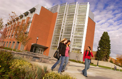 Three students walking in front of building.