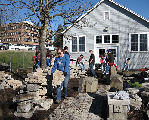 Students carying rocks in a garden area